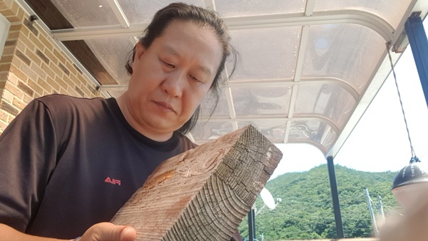 진성영 캘리그래피 작가가 고향 전남 진도군 조도에서 버려진 바다 폐목재를 활용하여 명패를 제작하고 있다. ⓒ진성영
